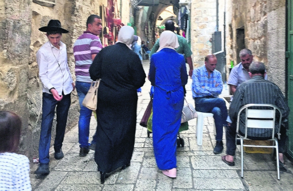 Convivencia: un joven judío ortodoxo camina junto a un grupo de mujeres árabes en la zona del mercado de Jerusalém. Foto: El País