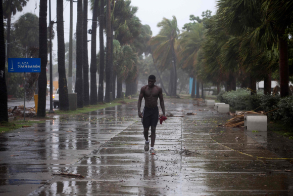 Un hombre camina bajo lluvia torrencial durante tormenta Isaías en Santo Domingo. Foto: AFP