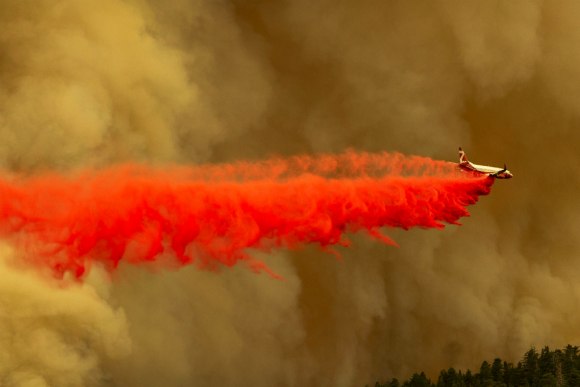 Productos para frenar el fuego son lanzados desde un avión en la zona del Bosque Nacional Angeles, en el estado de California. Foto: AFP
