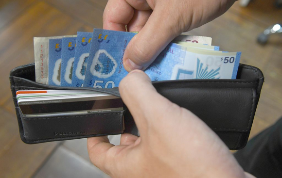 Hombre contando billetes de 50 pesos uruguayos en su billetera. Foto: Darwin Borrelli