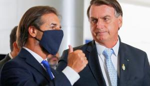 Lacalle Pou devuelve un saludo mientras es observado por el presidente Bolsonaro. Foto: AFP