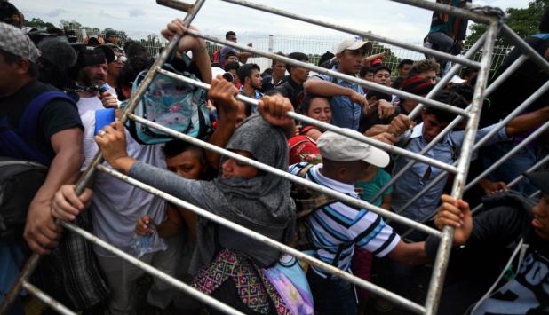 Migrantes hondureños presionan y logran derribar las vallas sobre el puente el puente que cruza el río Suchiate. Foto: AFP